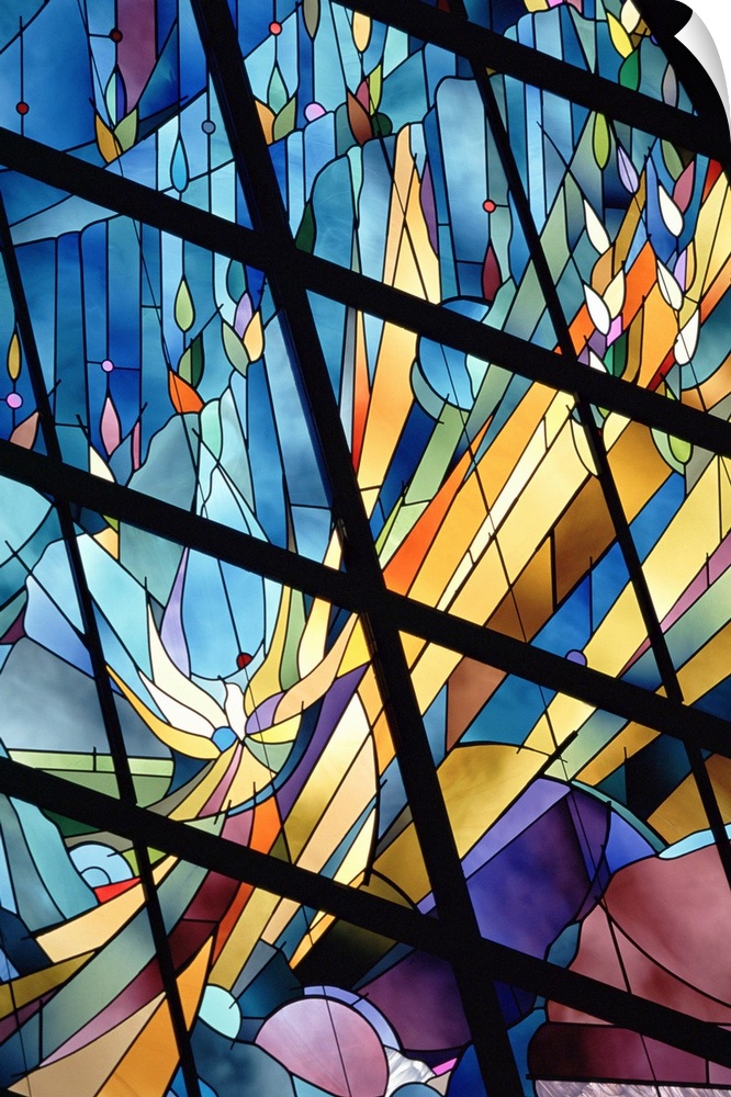 Photograph of a close-up view from below of a bright stained glass window.