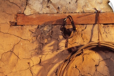 Still Life Of Spurs And Lasso Hanging On Adobe Wall