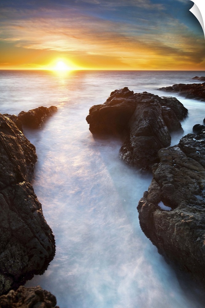 Sunset at seashore with rocks and surf, US.