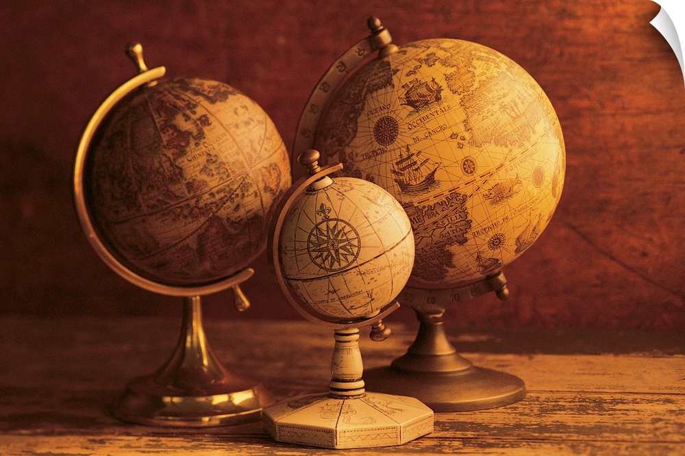 Photograph of three vintage globes of varying sizes sitting on a map table.