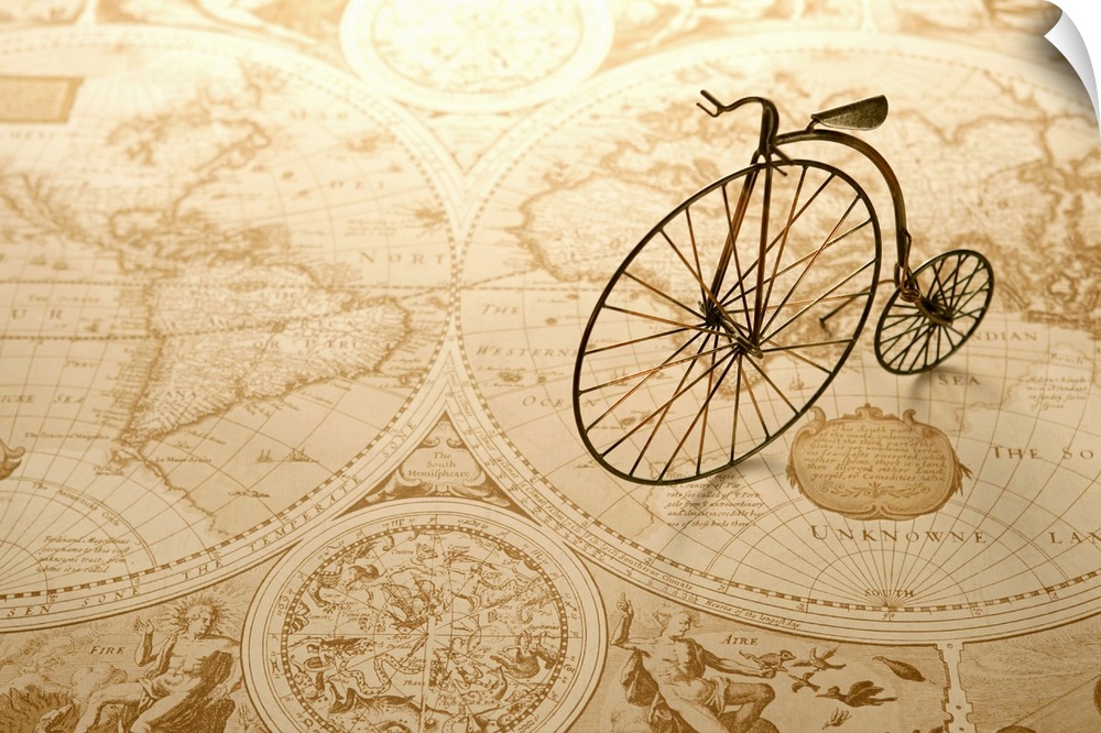 An antique toy bike on top of an old map of the world.