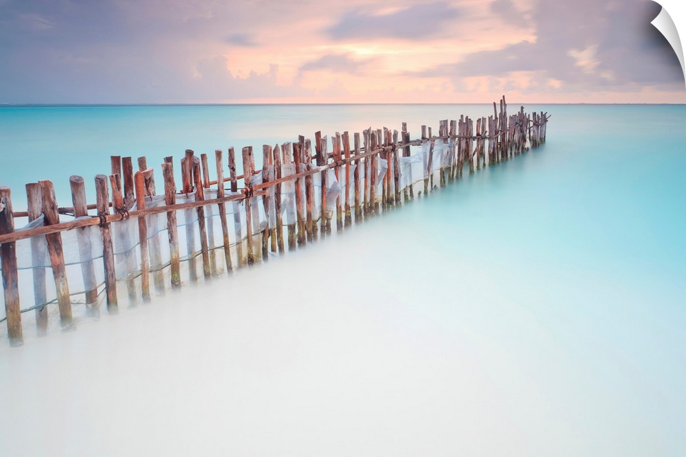 Tranquil scene of Wooden posts in Caribbean sea, at sunset right after storm.