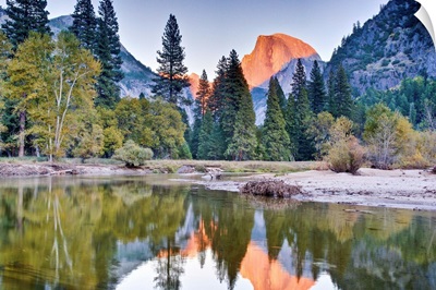 Trees and mountain reflection in river.