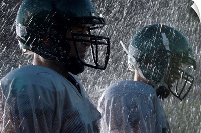 Two American football players in rain, side view
