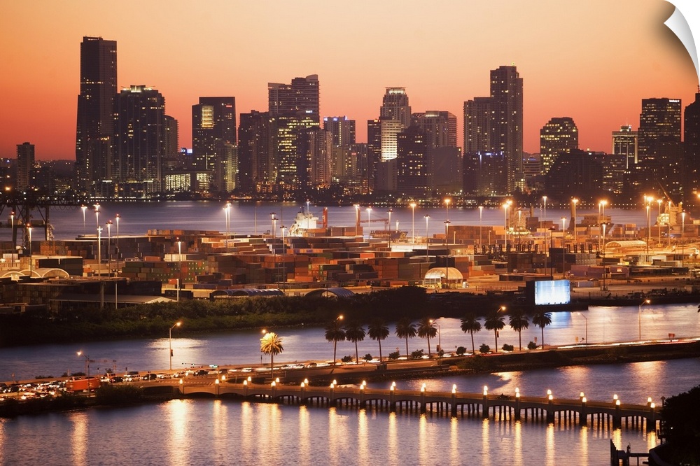 Photograph of skyline and waterfront with buildings lit up at dusk.