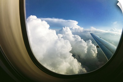 Watching the clouds pass by through a window of an airplane
