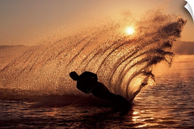 Water-skier at sunset sending up spray of water