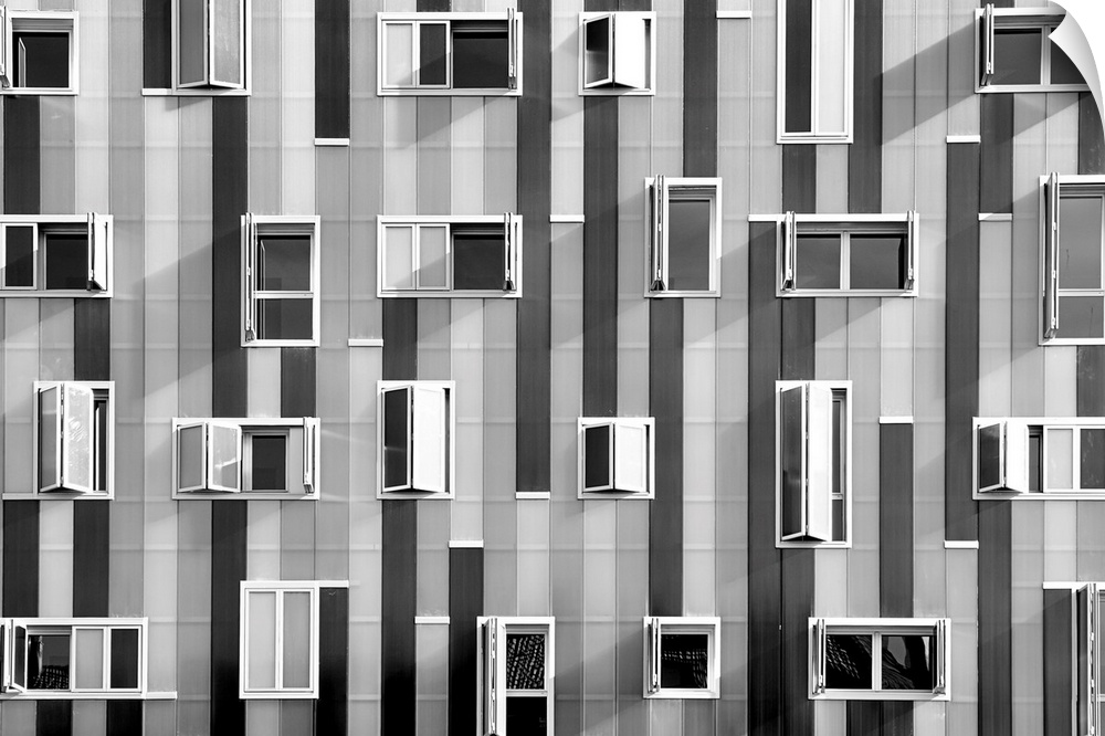 Black and white photograph of windows on the side of a building that are scattered about in no particular pattern.