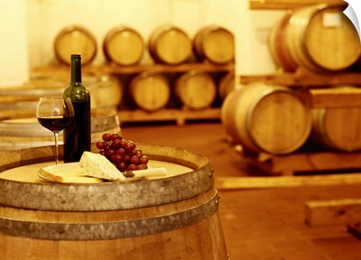 wine bottle with a wineglass and cheese on a barrel