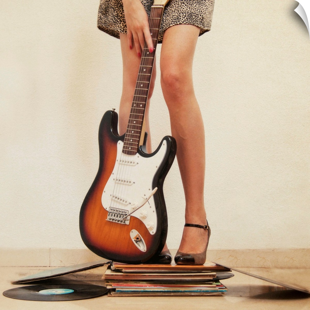 Woman holding guitar and standing on books, close-up.