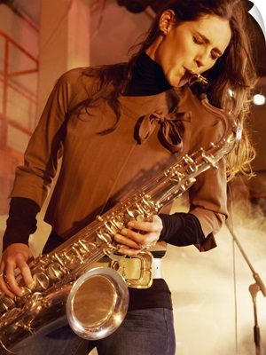 Woman Stands on a Smoky Stage Playing a Saxophone With Passion
