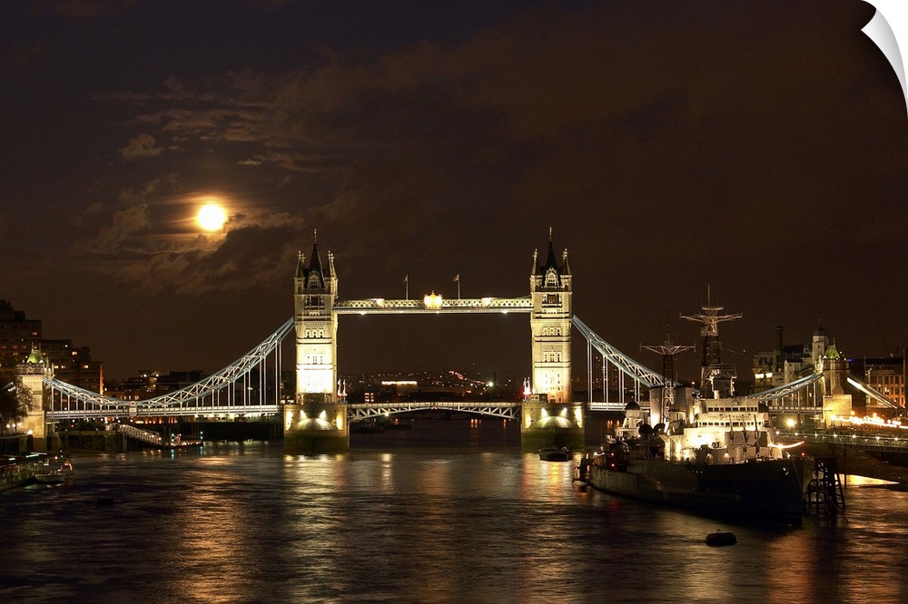 The dramatic view looking east along the river Thames past the World War Two warship HMS Belfast towards a full moon risin...