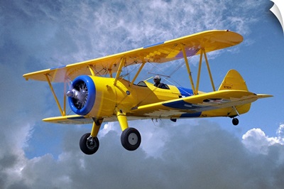 Yellow Stearman 5YP bi-plane flying in cloudy sky