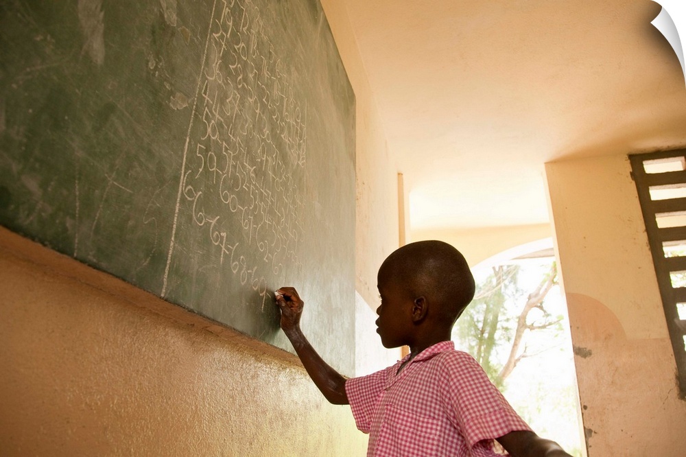 Young male 5-7 in Haiti writing on a blackboard in school
