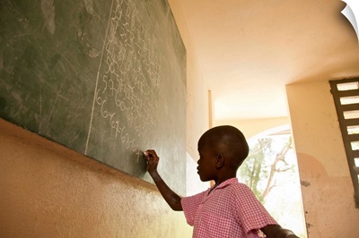 Young boy in school writing on chalkboard