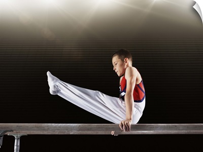 Young male gymnast performing on parallel bars