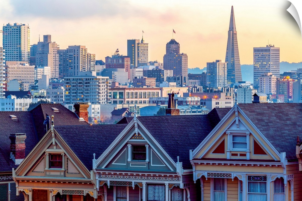 Photography of a pastel-colored row of houses with the San Francisco skyline in the background.