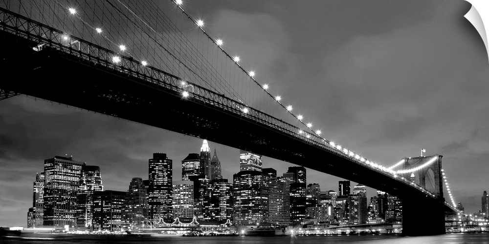 Black and white panoramic of the Brooklyn Bridge with New York City in the background.
