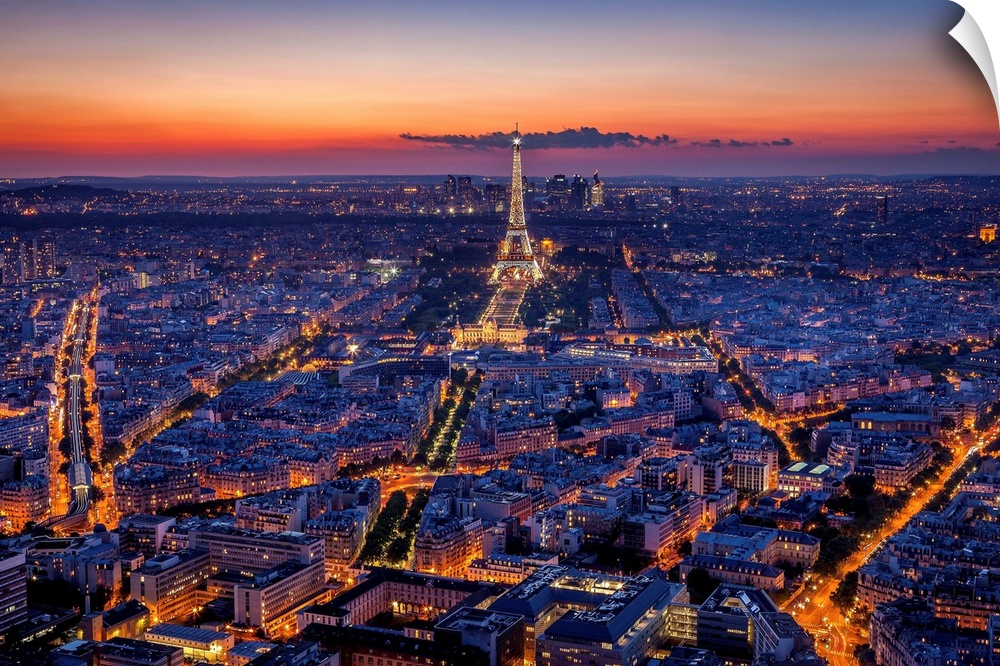 An aerial photograph of Paris at night with the Eiffel tower seen standing tall.