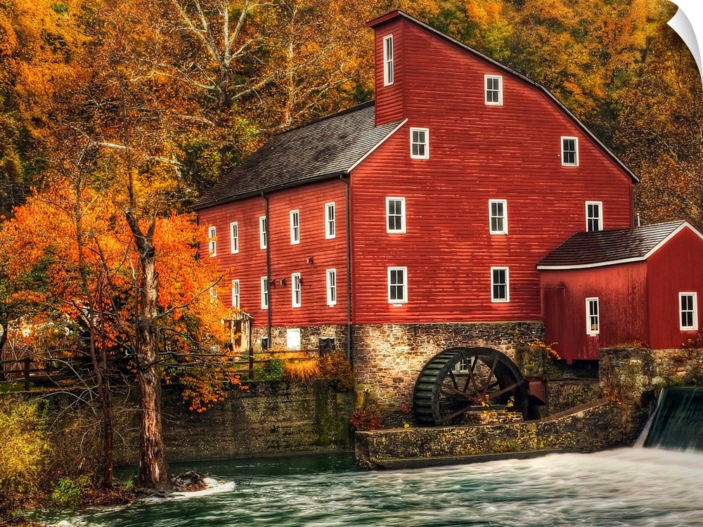 A Photograph of an old rustic looking watermill. With rushing water in the foreground.