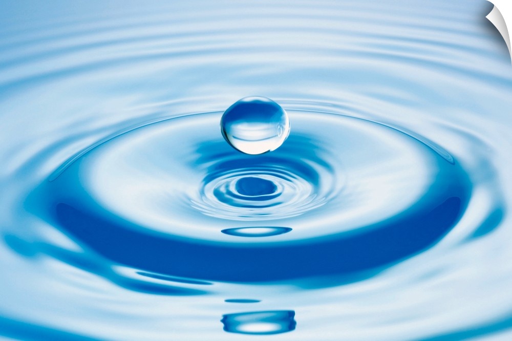 Horizontal close up photograph of a drop of water with ripples.