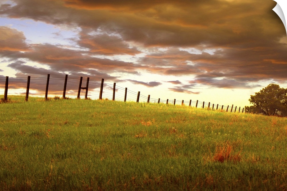 Sunset with dramatic clouds over a fenced field, near Custer State Park, South Dakota.
