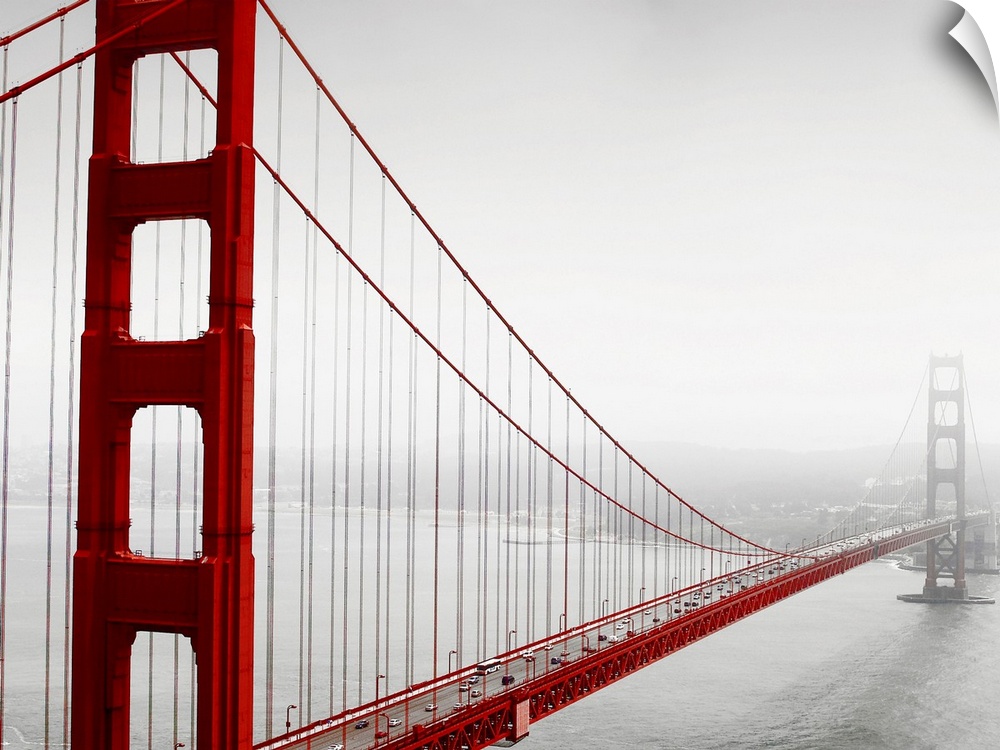 Horizontal photograph of the Golden Gate Bridge in fog in black and white with selective color on the bridge.