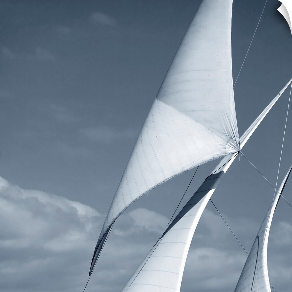 Black and white photograph of three sails against a cloudy sky.