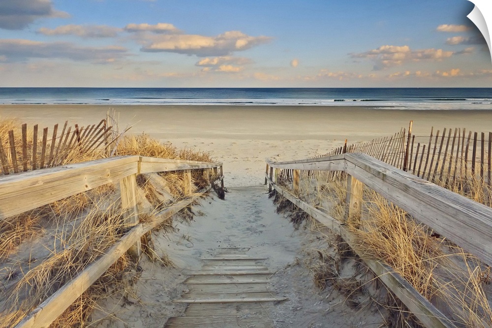 A photograph of an idyllic scene with a wooden walkway leading down to a sandy secluded beach.