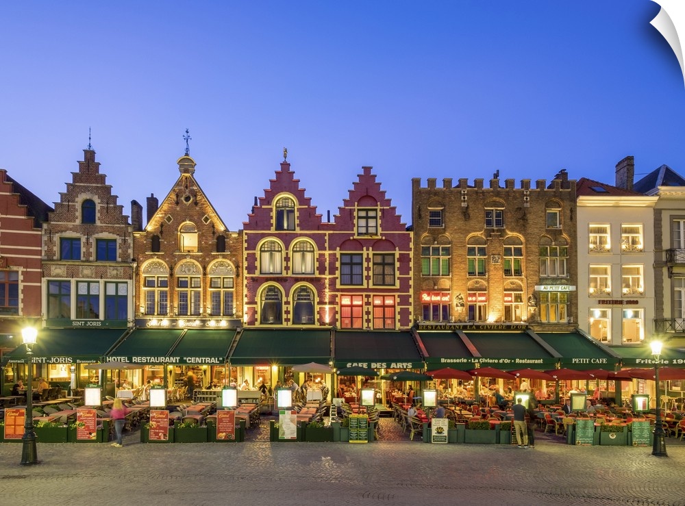 Belgium, West Flanders (Vlaanderen), Bruges (Brugge). Medieval guild houses and restaurants on Markt square at dusk.