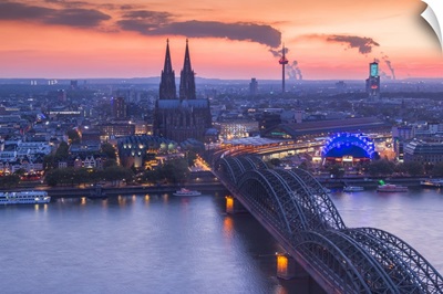 Cologne Cathedral and Hohenzoller Bridge over River Rhine in Cologne city at dusk.