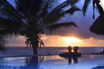 Couple relaxing inside infinity pool overlooking the beach at luxurious resort