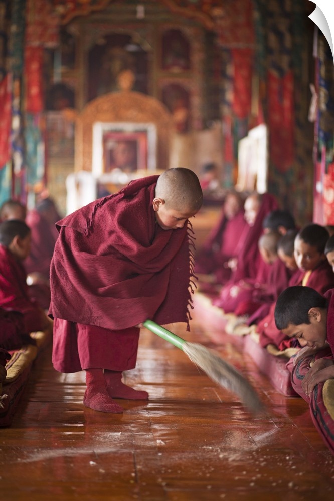 India, Ladakh, Thiksey. Young novice monk sweeping up the tsampa crumbs at morning prayers or puja, Thiksey Monastery.