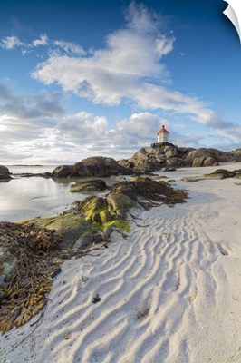 Midnight sun lights up lighthouse on cliffs surrounded by sea and sand, Norway