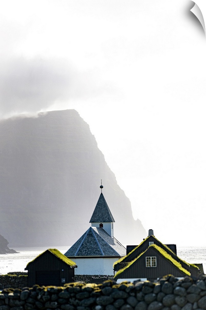 Misty sky over the traditional church of Vidareidi ovelooking a fjord, Vidoy Island, Faroe Islands