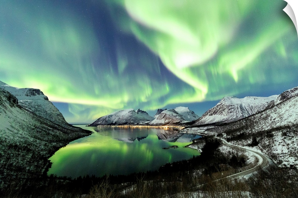 Northern lights and stars light up the snowy peaks reflected in the cold sea Bergsbotn Senja Troms Norway Europe