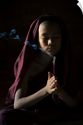 Novice Monk Holding A Lit Incense Stick While Praying Inside A Temple, Bagan, Myanmar
