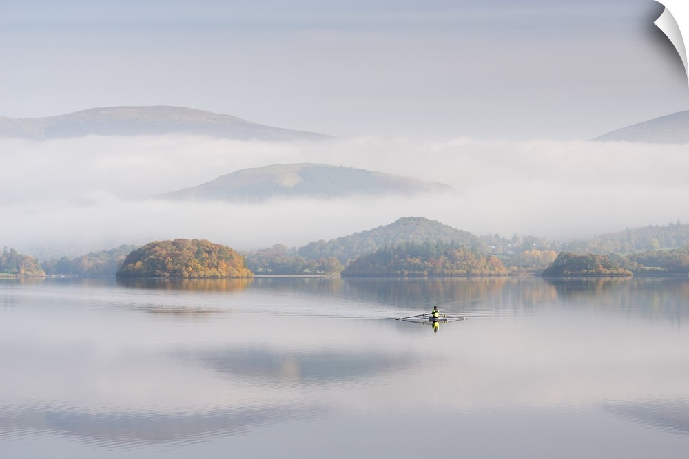 Single sculler rowing across a misty Derwent Water at dawn, Lake District, Cumbria, England. Autumn (October) 2016.