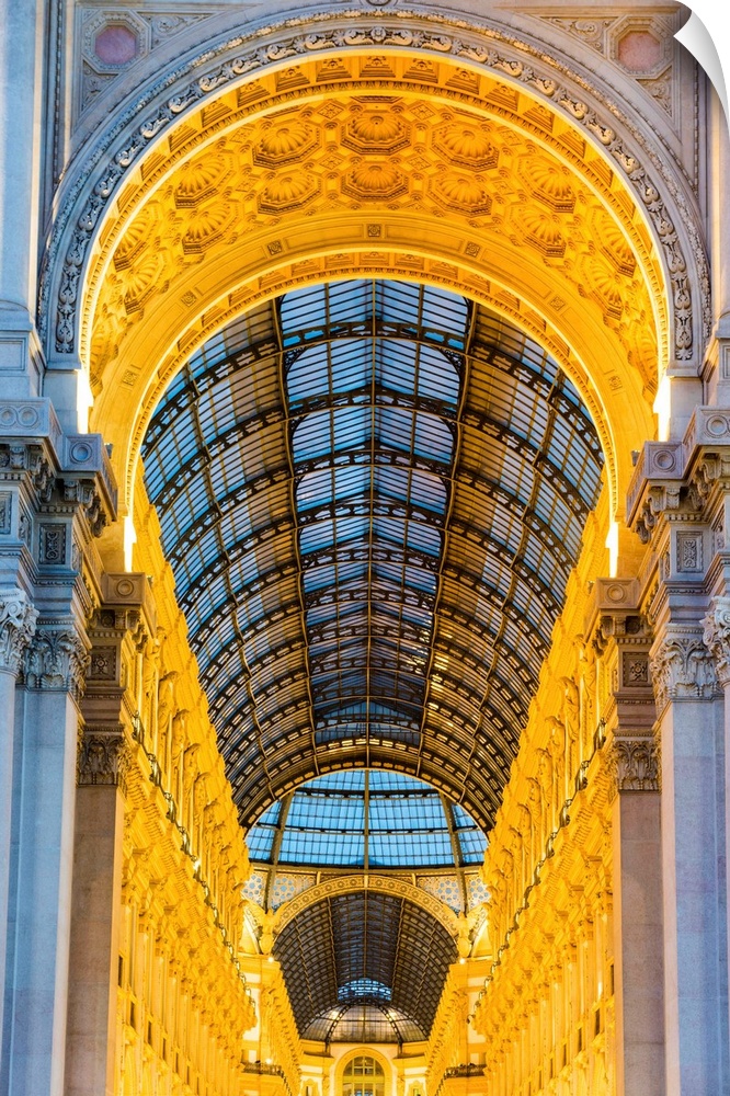 Milan, Lombardy, Italy. The entrance to the Galleria Vittorio Emanuele II illuminated at dusk.