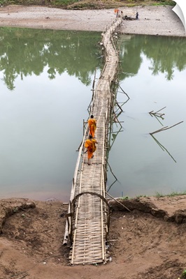 Two buddhist monks walk across bamboo bridge, Luang Prabang, Laos