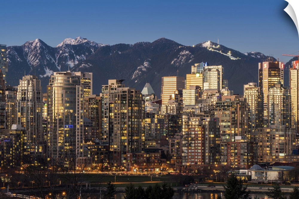 Downtown skyline with snowy mountains behind at dusk, Vancouver, British Columbia, Canada.