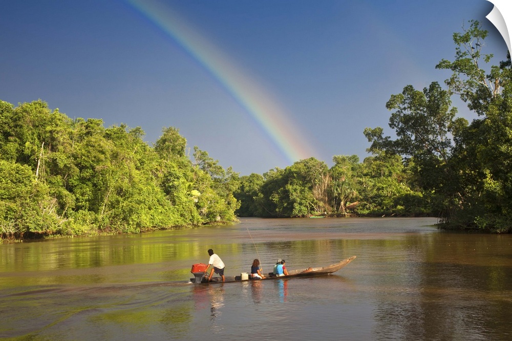 Venezuela, Delta Amacuro, Orinoco Delta, Warao People in boat on Nararina river with rainbow in stormy sky
