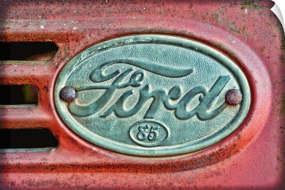 Oversized, horizontal photograph of a Ford emblem attached to an old, rusty 1930's Ford F38.