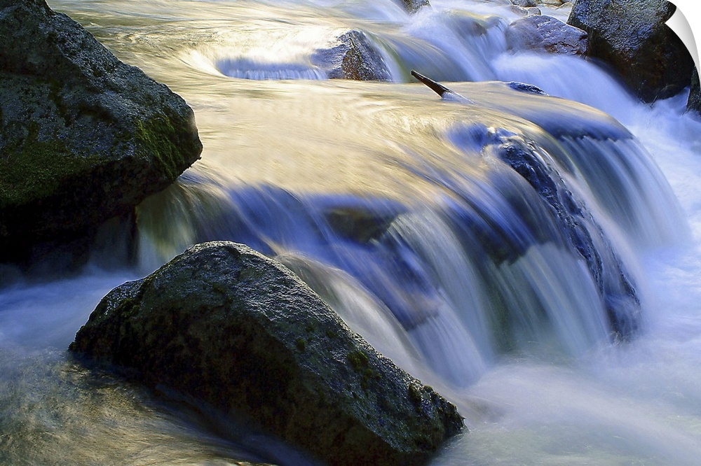 Long exposure shot of water in a stream rushing over a rocky riverbed, creating a small waterfall.