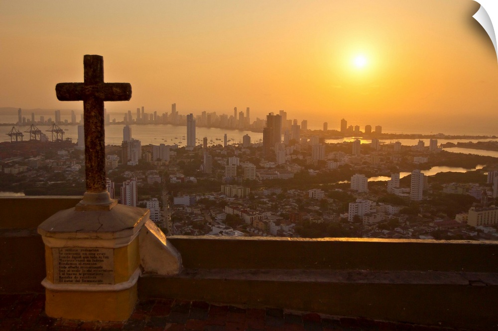 A cross with the Cartagena skyline in the distance at sunset.