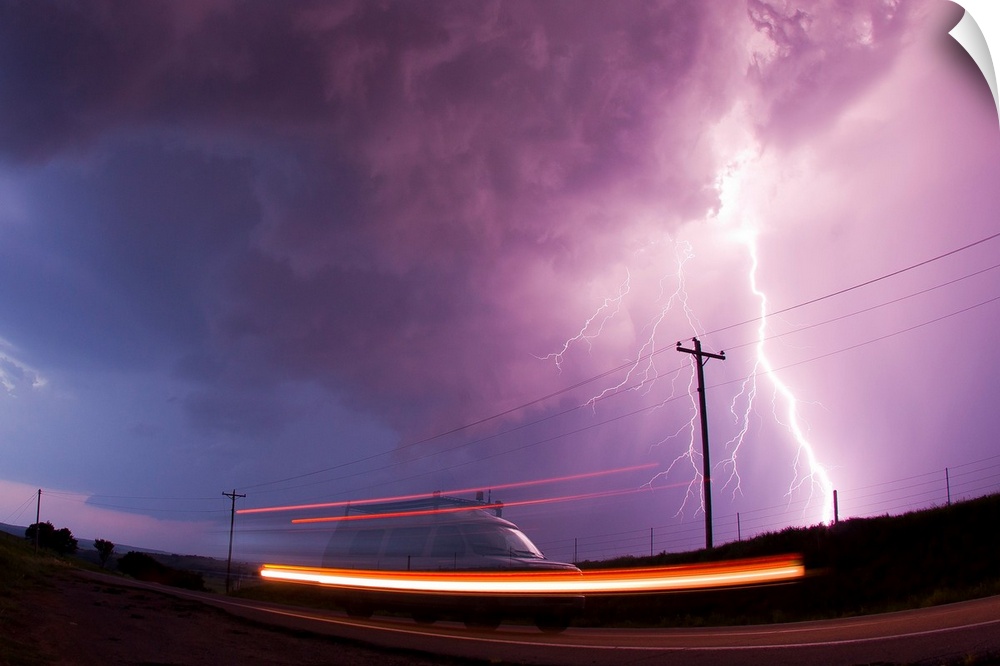 A large lightning bolt strikes behind a storm chaser's moving van.