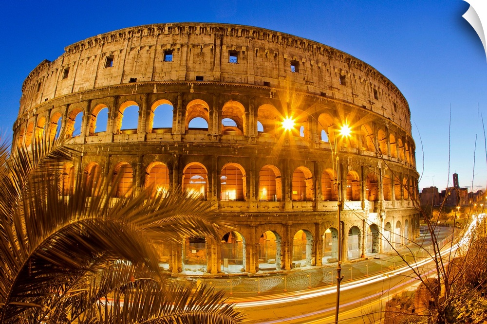 The ancient Roman Colosseum casts an illuminated golden light at dusk.