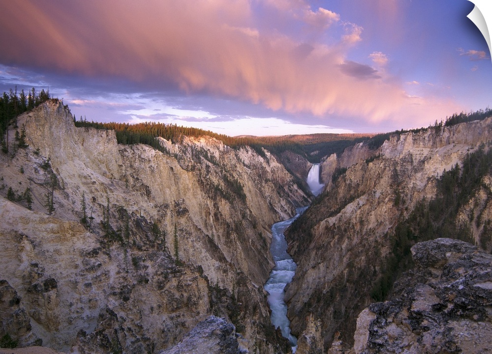 Lower Yellowstone Falls running through a valley in Yellowstone National Park with the sunset hitting the upper cliffs.
