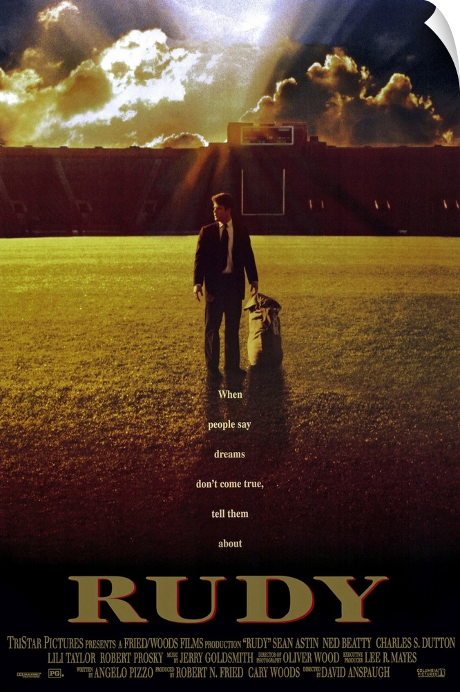 This large vertical piece is a movie poster for "Rudy". It pictures the star character walking across the football field i...