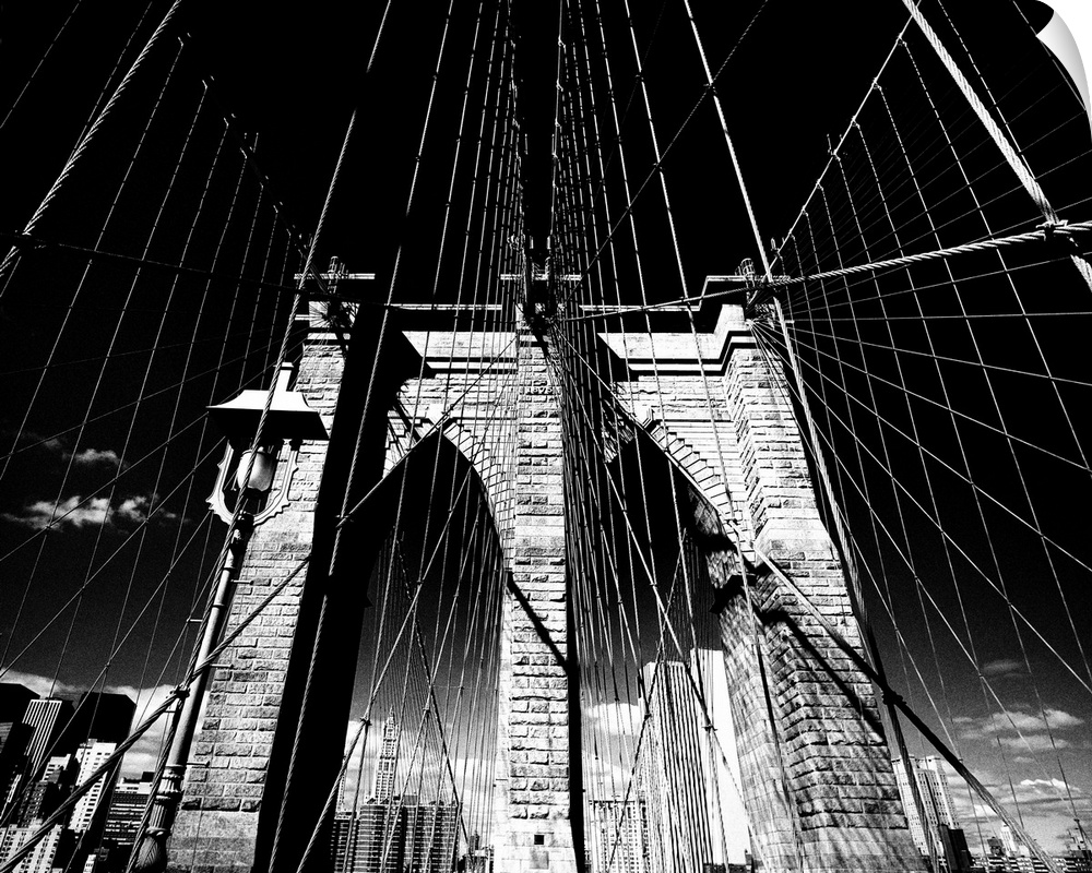 Dramatic black and white photograph of the Brooklyn bridge arches and suspension cables.